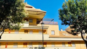 A multi-story building with balconies, a flat roof, and a street lamp. - Sea Breeze Apartment | Spacious Terrace (Fuengirola)