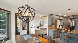 A modern kitchen with a central island, pendant lighting, and a view to a dining area. - Spacious East Vail Getaway by Vail Butler (Vail)