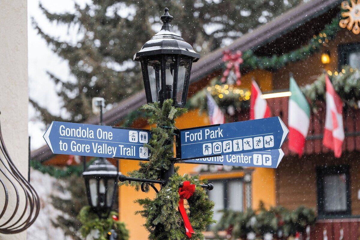 Directional signs for Gondola One to Gore Valley Trail and Ford Park, with a Christmas wreath and a lamp post.