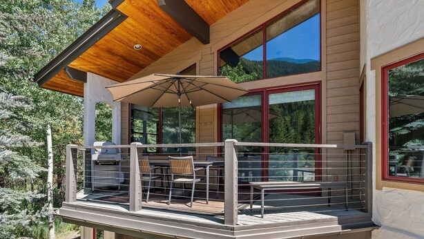 A modern building with a balcony, outdoor seating, and large windows. - Spacious East Vail Getaway by Vail Butler (Vail)