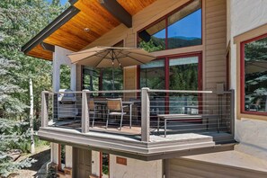 A modern building with a balcony, outdoor seating, and large windows.
