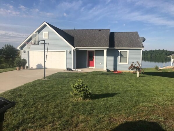 A single-story house with a garage, a red door, and a small lawn.