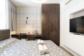 Relax in a stylish room with a neatly made bed, flat-screen TV, and comfortable workspace.