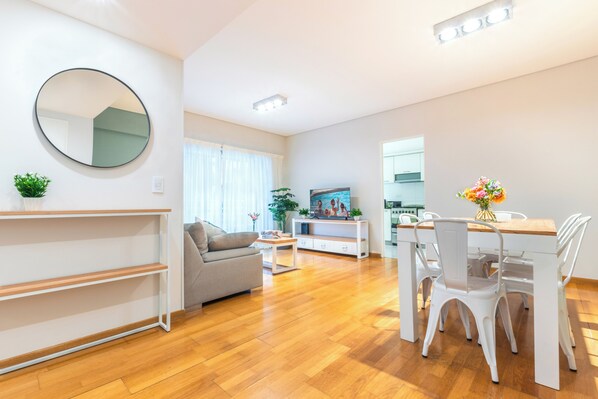 Uma sala de estar moderna com sofá, mesa de jantar, cadeiras e televisão.