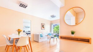 Ein modernes Wohnzimmer mit Essbereich, einer Couch, einem Couchtisch und einem Spiegel an der Wand.