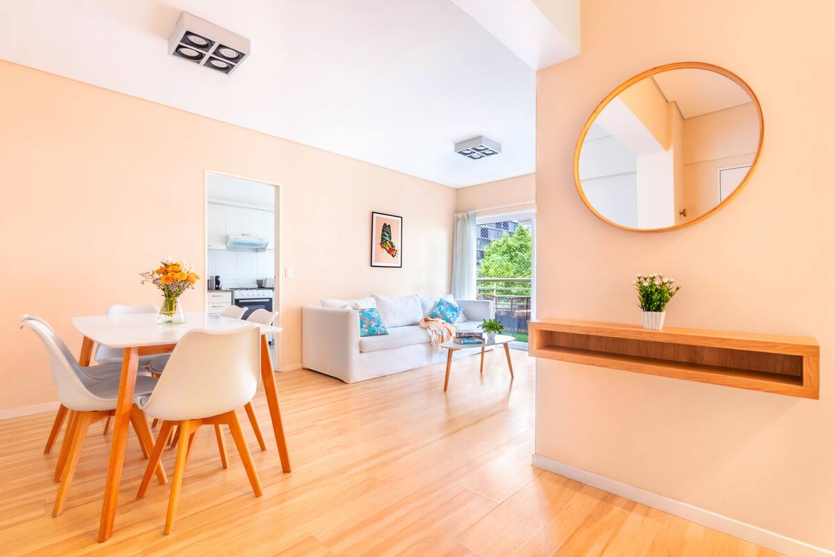 Una sala de estar moderna con comedor, un sofá, una mesa de centro y un espejo en la pared.