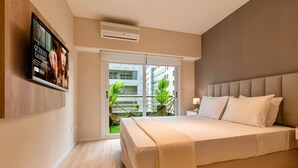 Un dormitorio con una cama grande, un televisor montado en la pared y una puerta corrediza de vidrio que da a un balcón.