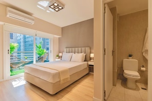A bedroom with a large bed, a bedside table with a lamp, and a view of a balcony with plants. - Modern Apartments in Puerto Madero (Buenos Aires)