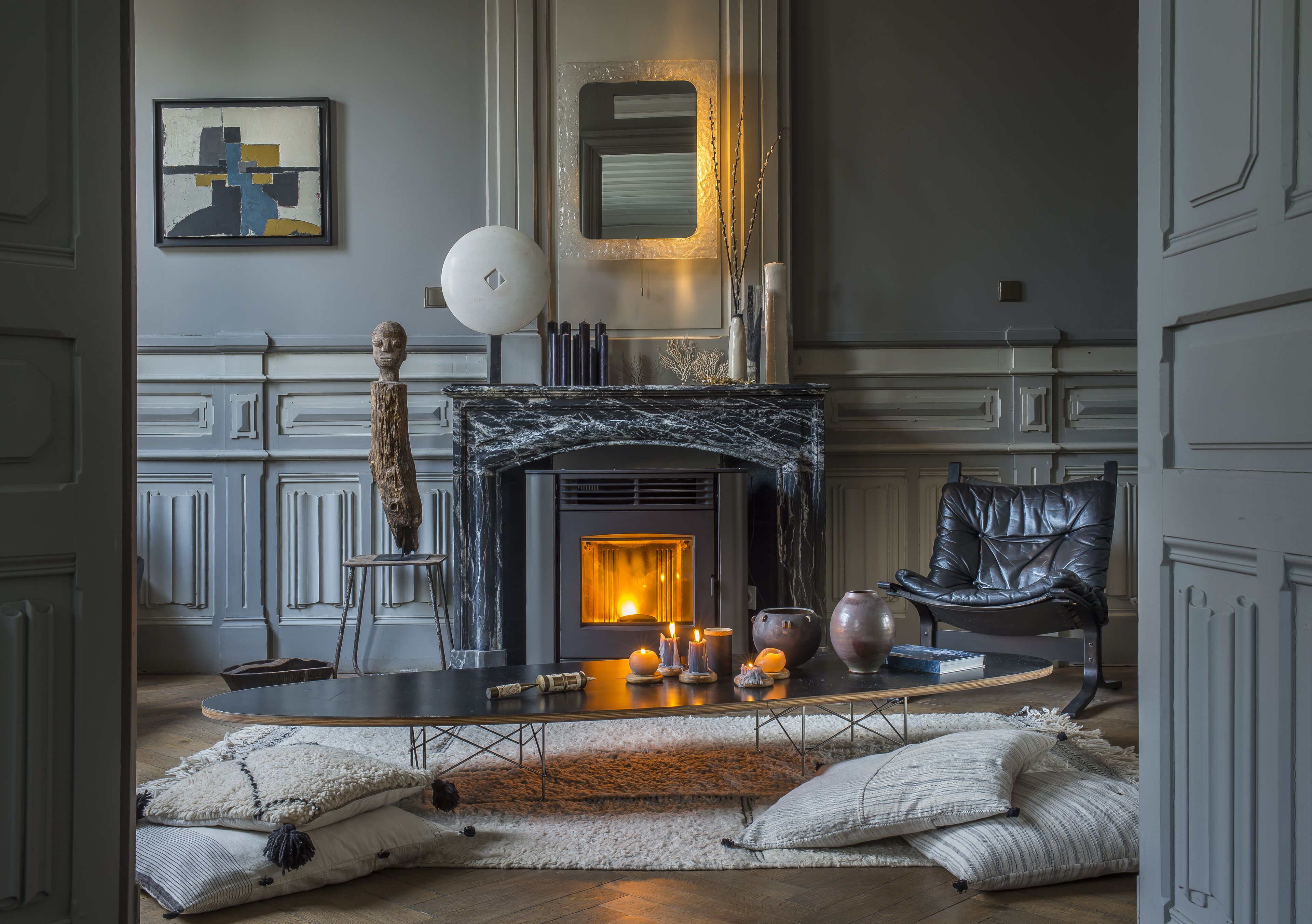 A cozy living room with a fireplace, a leather armchair, and a modern abstract painting.