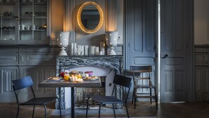 A dining area with a marble table, two chairs, a fireplace, and a cabinet with dishes. - LE LANTERNON (Saint-Martin-de-Re)