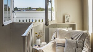 A cozy bedroom with a large window, a wicker pendant light, and a bedside table with a cup and saucer. - LE LANTERNON (Saint-Martin-de-Re)