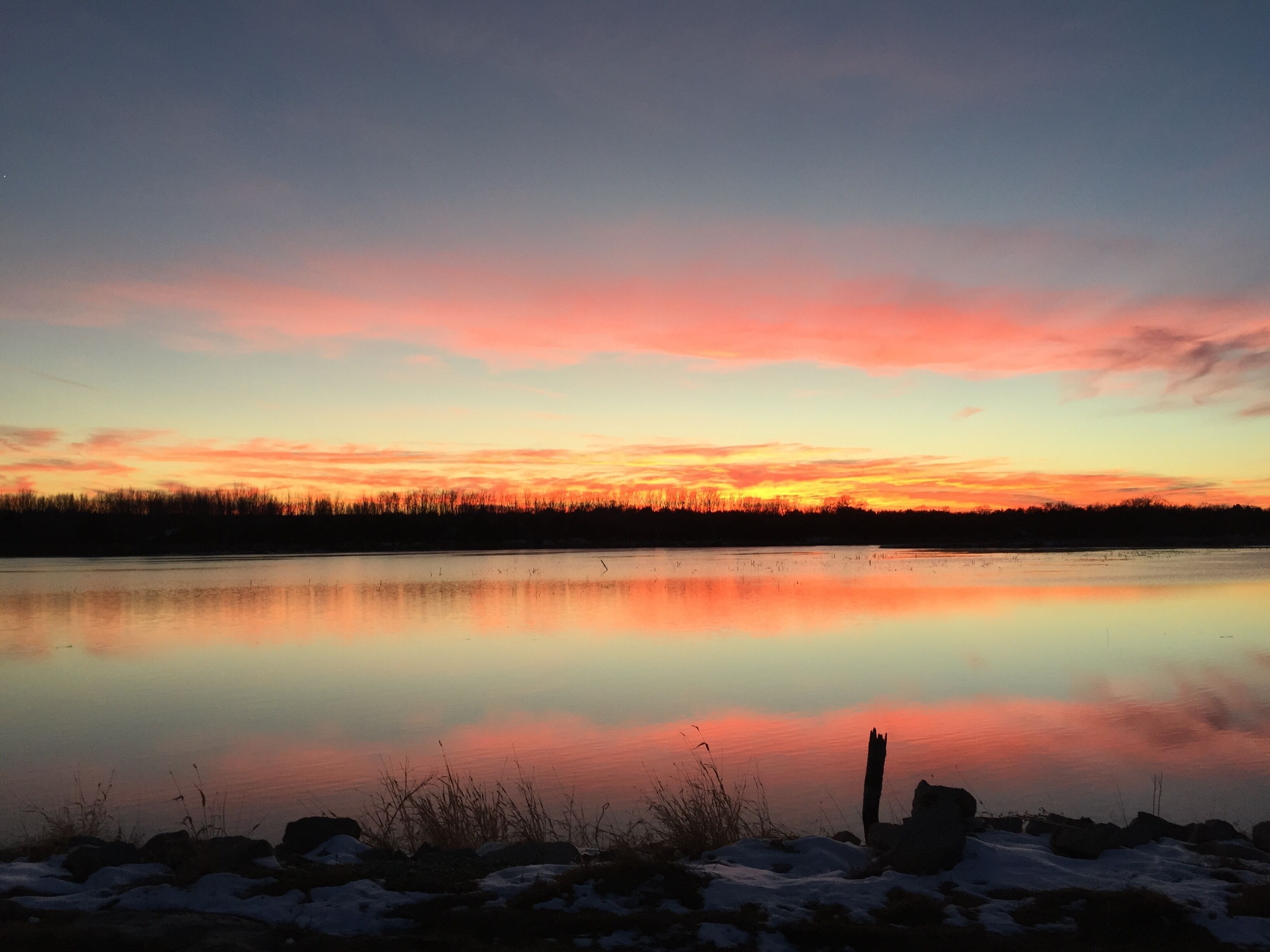 Un lago tranquilo al atardecer, con un reflejo nítido del cielo.