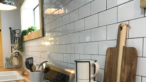 Une cuisine avec un dosseret de carrelage blanc, un plan de travail en bois, des appareils électroménagers en acier inoxydable et une machine à café.