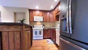 A kitchen with wooden cabinets, a white stove, a stainless steel refrigerator, and a microwave.