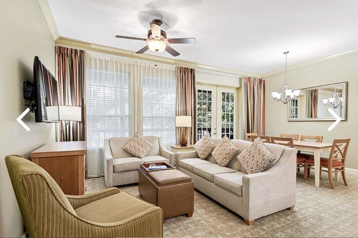 A living room with a sofa, armchair, coffee table, and a dining area with a table and chairs.