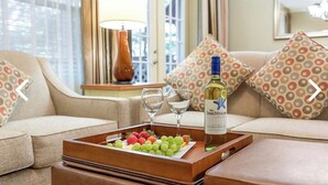 Un soggiorno accogliente con un divano, un vassoio con uva e una bottiglia di vino, e una lampada.