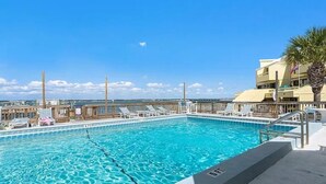 Ein Schwimmbecken mit klarem, blauem Wasser, Liegestühlen und einer Palme.