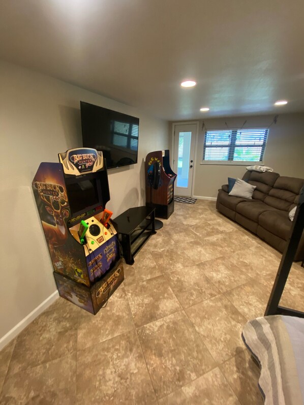 Un salon équipé d’une console de jeux, d’un canapé et d’un téléviseur fixé au mur.