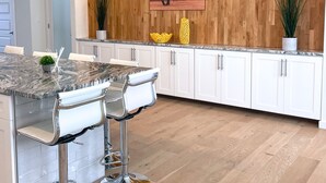 A modern kitchen with a marble countertop, white cabinets, and a wooden accent wall.