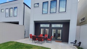 A modern two-story building with a patio area featuring outdoor seating and a small garden.