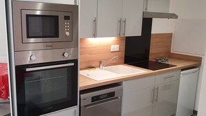 A modern kitchen with stainless steel appliances, grey cabinetry, and a wooden countertop. - 30 m2 furnished apartment near shops and metro (Sotteville-lès-Rouen)