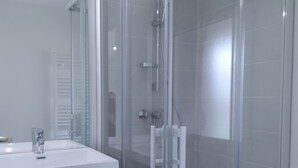 A modern bathroom with a glass-enclosed shower, a white sink, and a mirror. - 30 m2 furnished apartment near shops and metro (Sotteville-lès-Rouen)