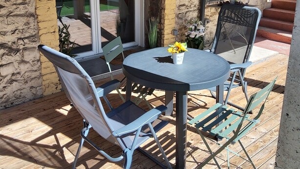 A patio with a round table and four chairs, a small potted plant, and a staircase leading to an upper level. - 30 m2 furnished apartment near shops and metro (Sotteville-lès-Rouen)