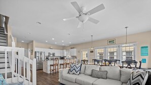 A spacious living area with a sofa, a dining table, and a kitchen in the background. - Oceanfront Family Retreat / Pool, Hot Tub, Elevator, Well stocked kitchen (North Topsail)
