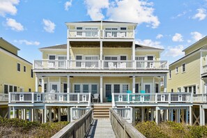A multi-story beachfront property with a wooden deck and balconies.