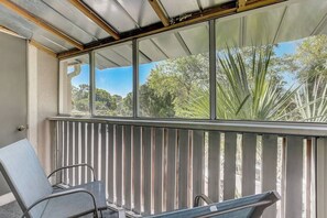A balcony with a metal railing, two chairs, and a view of trees and sky. - *Upscale 2/2 condo with pool 6 mins from IMG (Bradenton)