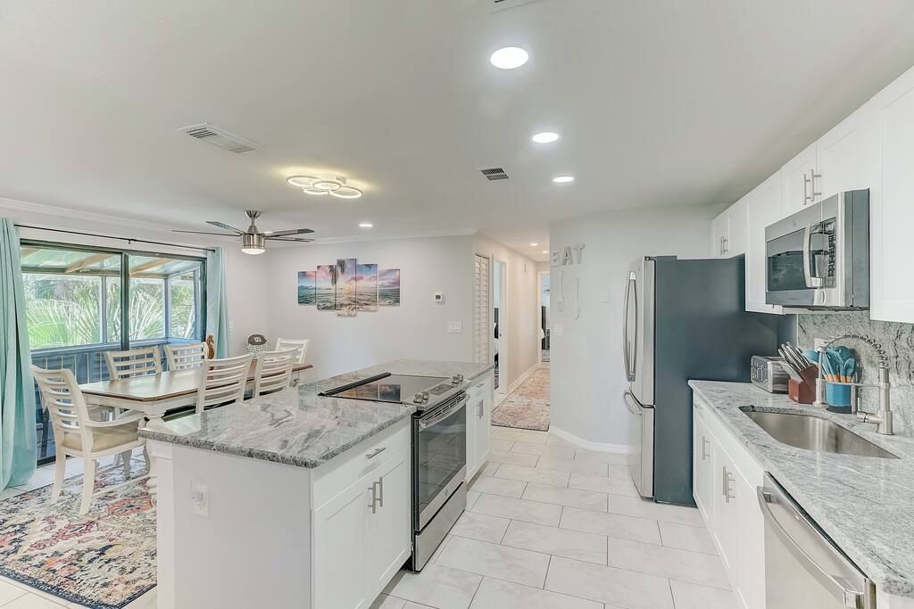 A modern kitchen with a central island, built-in appliances, and a dining area with a view.
