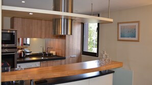 Eine moderne Küche mit Edelstahlgeräten, Holzschränken und einer schwarzen Arbeitsplatte.