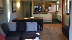 Ein Wohnzimmer mit einer Couch, einem Couchtisch und einer Küche im Hintergrund.