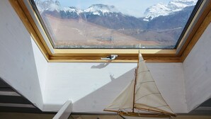 Ein Dachfenster mit Blick auf schneebedeckte Berge.