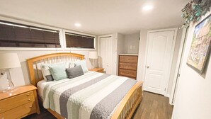 Un dormitorio con cama de madera, mesita de noche, cómoda y una puerta.