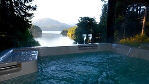 A hot tub with a view of a lake and mountains.