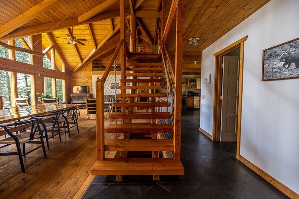 A spacious wooden interior with a central staircase, large windows, and a dining area. - Thimbleberry Bay House (Sitka)
