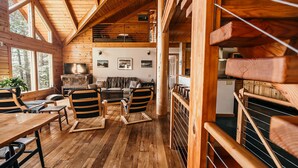 A wooden interior with a dining area, seating, and a TV.