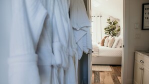 A bedroom with a bed, a bedside table, a nightstand, a potted plant, and a wall-mounted light fixture. - 738 Alice Loop - 4 Sea's Cottage (Sitka)