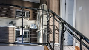 A modern kitchen with stainless steel appliances, a wooden staircase, and a view of the lower level. - 730 Alice Loop: 3  BR, 2  BA Duplex in Sitka, Sleeps 6 (Sitka)