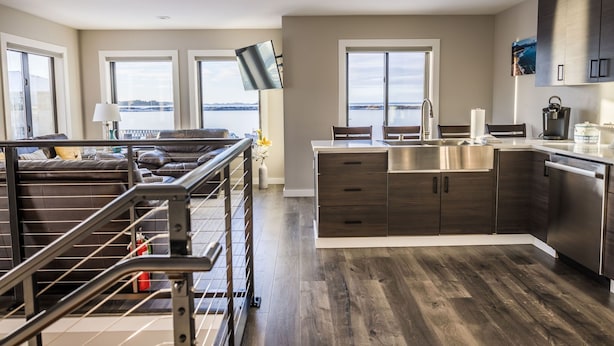 A modern kitchen with dark wood cabinets, a stainless steel sink, and a view of the water. - 730 Alice Loop: 3  BR, 2  BA Duplex in Sitka, Sleeps 6 (Sitka)