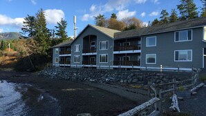 A multi-story building with balconies, situated by a rocky shoreline. - Admiralty Suite at Island View (Sitka)