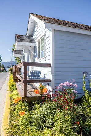 Situated on a scenic street, this charming home offers a front porch with a chair and beautiful flowering plants.