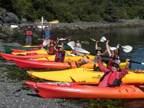 A group of people in kayaks lined up on a rocky shore. - Fishermans Quay North Bunkhouse (Sitka)