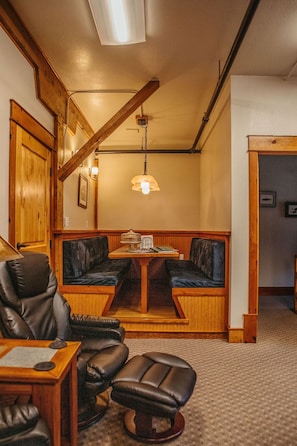 A cozy room with a wooden bench, a leather chair, and a small table with a lamp.