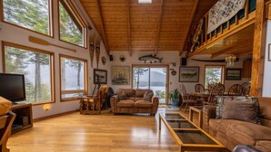 Un salon spacieux doté de parquets en bois, de grandes fenêtres et d’une cheminée accueillante.