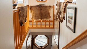 Un escalier avec des rampes en bois, un tapis en fourrure et un tableau encadré au mur.
