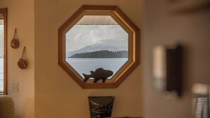 Une fenêtre hexagonale donnant sur une montagne et un lac.
