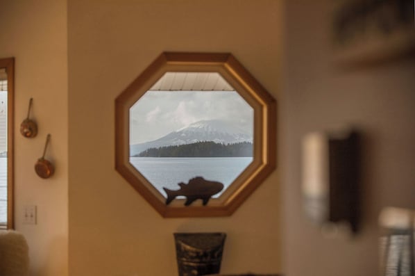 A hexagonal window with a view of a mountain and lake.