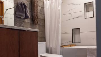 Ein modernes Badezimmer mit einem Holzkosmetikschrank, einer weißen Toilette und einer Marmorwand.